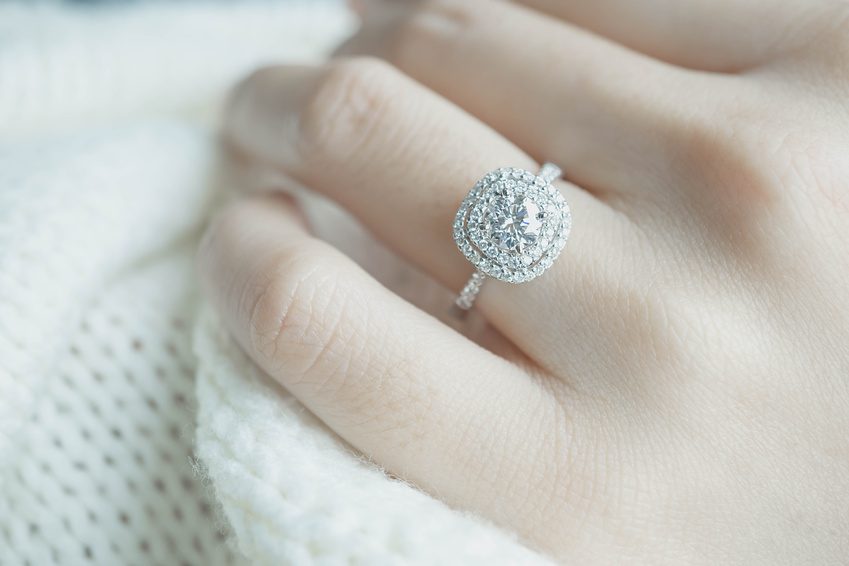 Close up Diamond ring on woman’s finger before wedding with white scarf background.(soft and selective focus)