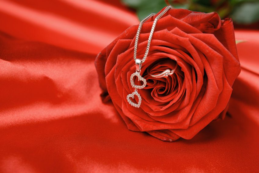 Valentine’s day necklace with two hearts pendant and a ring on red rose.