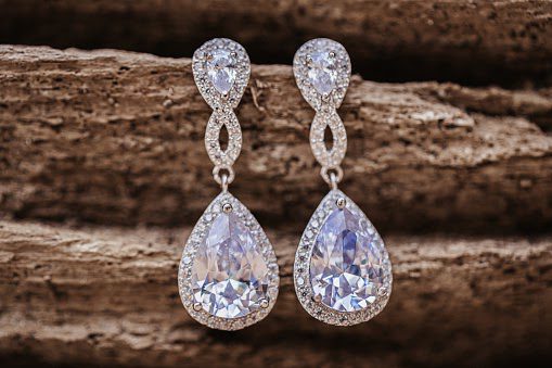 diamond wedding earrings hanging on wooden background, selective focus